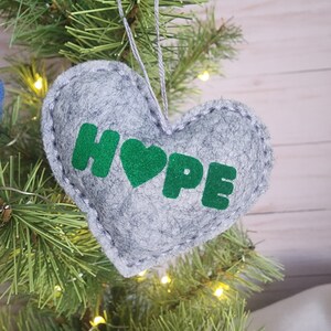May include: A gray felt heart-shaped ornament with the word "HOPE" in green felt letters and a green felt heart.