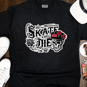 May include: Black t-shirt with a white graphic design that says "Skate or Die" with a skull wearing a red and white hat with roses.