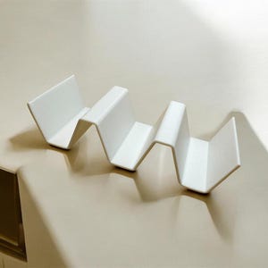 Puede incluir: Estante para platos de plástico blanco con un diseño ondulado. El estante está diseñado para sostener varios platos o platos.