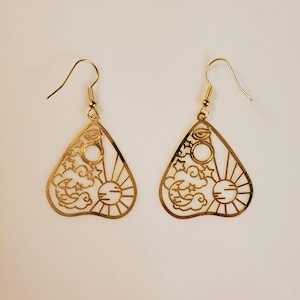 Brincos de metal dourado cortados a laser. Joia em formato de palheta de violão. Decorado com o sol e a lua sozinhos com o mau-olhado.