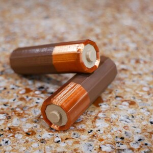 Puede incluir: Dos pilas AA de color marr&oacute;n y cobre.