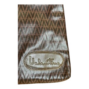 May include: A brown leather handbag with a brown and gold geometric pattern. The bag has a gold oval logo with the text "Valentino" on it.