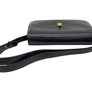 May include: A black leather shoulder bag with a gold clasp. The bag has a long adjustable strap.