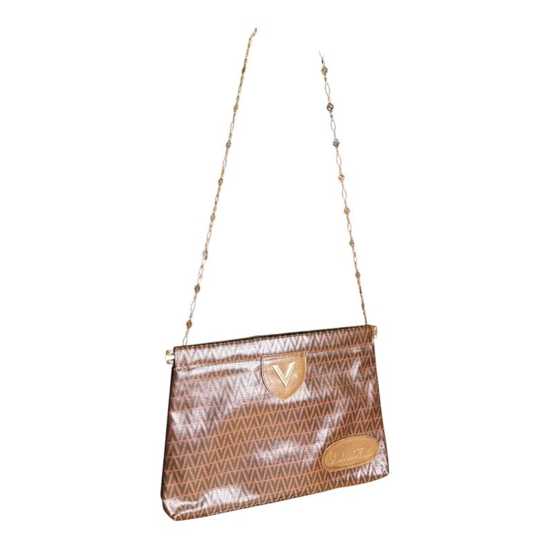 May include: A brown and tan leather shoulder bag with a gold chain strap and a V-shaped logo. The bag has a brown and tan geometric pattern.