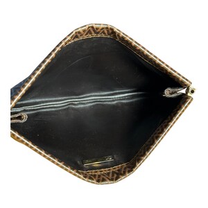 May include: The inside of a brown and black patterned clutch bag with a black lining. The bag has a gold zipper.