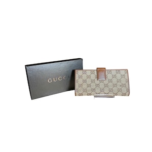 May include: A brown and beige Gucci wallet with a brown leather flap and the Gucci logo on the box.
