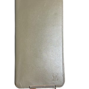 May include: A green leather wallet with a Louis Vuitton logo embossed on the front.