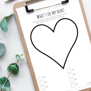 May include: A clipboard holds a white sheet with a large heart outline and the text "WHAT'S IN MY HEART". Boxes and lines for colour-coding feelings are below the heart. A silver pen lies at the top.