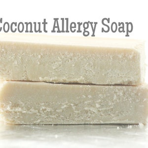 以下が含まれることがあります： 白くて四角い石鹸が2つ積み重ねられています。石鹸には「ココナッツアレルギー用石鹸」と書いてあります。