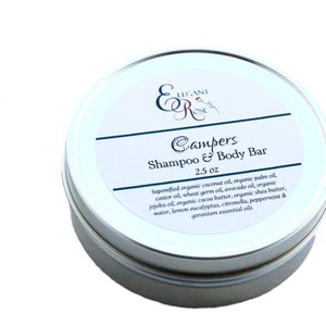 Könnte beinhalten: Eine silberne Blechdose mit einem weißen Etikett, auf dem "Campers Shampoo & Body Bar 2.5 oz" steht. Das Etikett listet die Inhaltsstoffe auf, darunter Kokosnussöl, Palmöl, Rizinusöl, Weizenkeimöl, Avocadoöl, Jojobaöl, Kakaobutter, Sheabutter, Wasser, Zitronen-Eukalyptus, Zitronengras, Pfefferminze und Geranien-ätherische Öle.