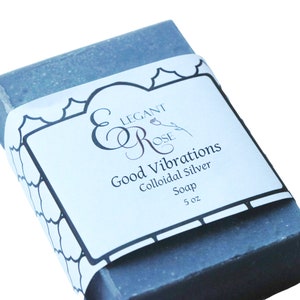 Op de afbeelding: Een grijze zeepstaaf met een wit etiket waarop "Elegant Rose" en "Good Vibrations Colloidal Silver Soap 5 oz" staat.