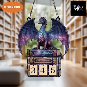 May include: A fantasy-themed hanging ornament featuring a purple dragon with outstretched wings, perched atop a stack of books. The books read "Books Read This Year" and "Sophia's Library." The ornament includes a counter with the numbers 3, 4, and 5.