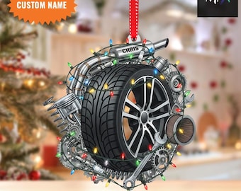 May include: A Christmas tree ornament with a car wheel design, engine components, and fairy lights. The name "CHRIS" is displayed, along with the text "CUSTOM NAME" and "2D FLAT ITEM".