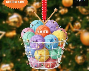 May include: A Christmas ornament featuring a white wire basket filled with colorful yarn balls. The ornament includes knitting needles, a red ribbon, and the text "SMITH" on an orange ball of yarn. The text "CUSTOM NAME" and "2D FLAT ITEM" are also visible.