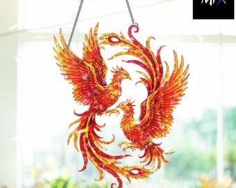 May include: A stained glass suncatcher featuring two phoenixes in shades of red, orange, and yellow. The birds are facing each other with outstretched wings and flowing tail feathers. The suncatcher hangs from a silver chain. The text "The Mix" is in the upper right corner.