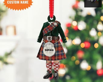 May include: A Scottish kilt Christmas ornament featuring a green jacket, tartan kilt, and a sporran with the name "SOPHIA". It hangs from a red and white polka dot ribbon. The text "CUSTOM NAME" is on a starburst shape.