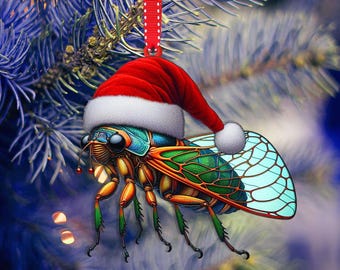Puede incluir: Adorno navideño de cigarra con gorro de Papá Noel rojo y cinta para colgar. El insecto presenta un diseño detallado con tonos verdes, azules, naranjas y marrones. El adorno cuelga de una rama de pino navideño azul-verdoso.
