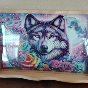 May include: Wooden serving tray featuring a detailed image of a wolf's face surrounded by colorful roses and floral accents. The wolf's fur is embellished with purple and pink beads. The tray has a light wood finish and curved handles.