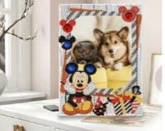 May include: A rectangular diamond painting kit featuring a central photograph of a dog and a cat, framed by a border decorated with Mickey Mouse icons in red, blue, and black, along with gift boxes and a striped pattern on a white background.