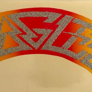 May include: A decal featuring the word EAGLES in a silver glitter texture. The letters are arranged in an arched shape against a background that transitions in color from green on the left to yellow, orange, and red on the right side.