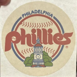 May include: A vintage Philadelphia Phillies baseball sticker with a red, white, and blue color scheme. The sticker features the team's logo, a baseball, and the Liberty Bell. The text "Philadelphia Phillies" is written in a retro font.