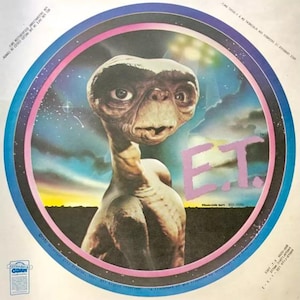 May include: A round sticker featuring a close-up of E.T. the Extra-Terrestrial, a fictional alien character from the 1982 film E.T. the Extra-Terrestrial. The sticker has a pink, white, and blue background with a starry sky and clouds. The text "E.T." is written in purple letters.