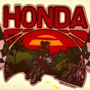 May include: Vintage Honda motorcycle sticker featuring a red sunset scene with a rider on a motorcycle. The word "HONDA" is in red block letters above the scene, with checkered flags on either side.