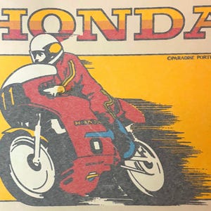 May include: A graphic print featuring the word HONDA in a retro orange and red gradient font above a stylized illustration of a rider in a red suit and white helmet on a red motorcycle with the number 11, set against a yellow background.
