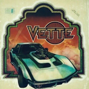 May include: A vintage-style poster featuring a light blue sports car with a prominent engine protruding from the hood. The word VETTE is printed in large, bold letters above the car, set against a decorative frame with a sunset-colored background.