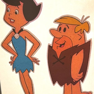 May include: A sticker featuring two cartoon characters: a female figure with black hair and a blue dress, and a male figure with blonde hair and a brown tunic. Both characters are barefoot. The text 1994 HBPI is printed near the base of each figure.