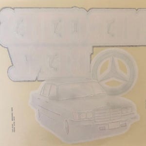 K&ouml;nnte beinhalten: Wei&szlig;er Vintage-Autoaufkleber mit dem Text "German Wheels" und einem stilisierten Mercedes-Benz-Logo.