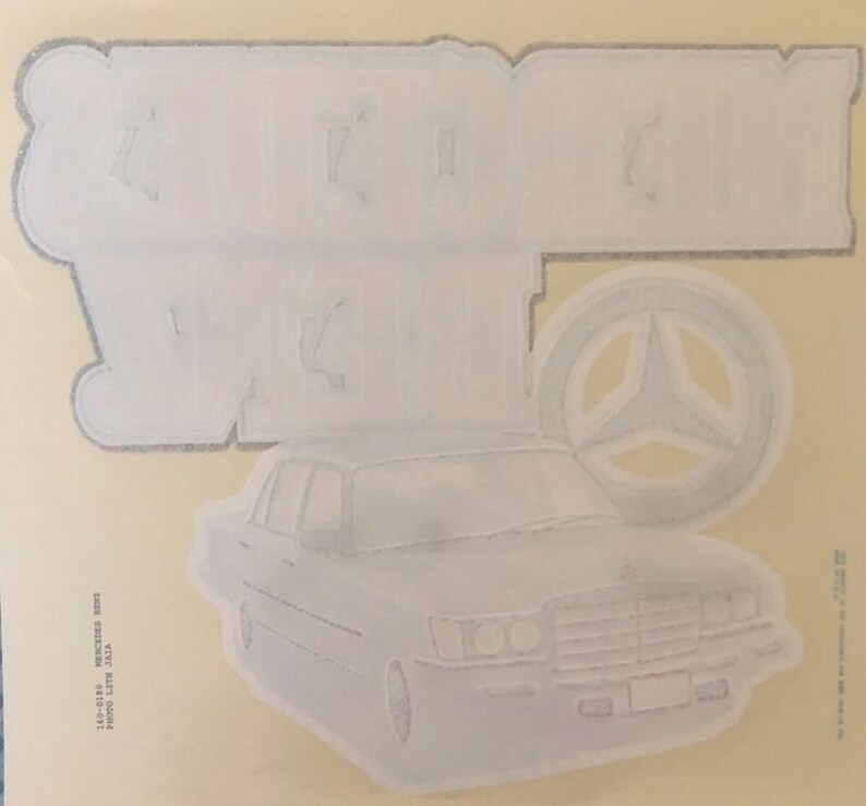 K&ouml;nnte beinhalten: Wei&szlig;er Vintage-Autoaufkleber mit dem Text "German Wheels" und einem stilisierten Mercedes-Benz-Logo.