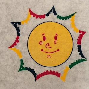 May include: A yellow sun with a smiling face, surrounded by a colorful starburst design with red, green, black, and yellow accents.
