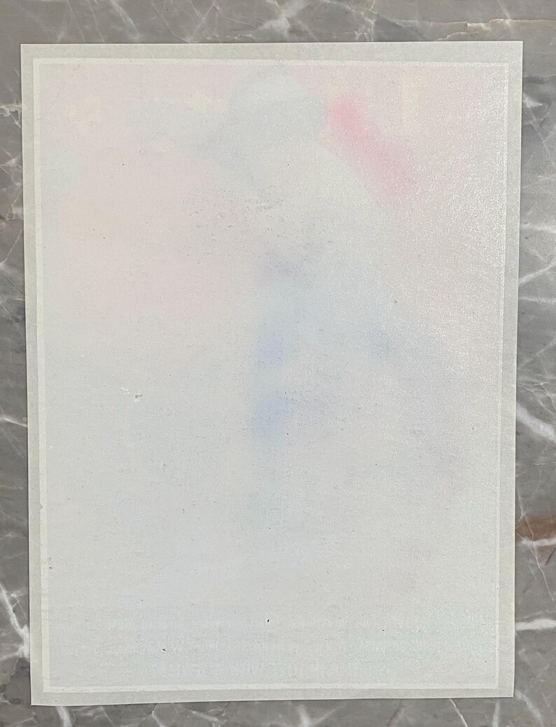May include: A rectangular, white paper with a faint watercolour design in pink, blue, and purple hues. The paper has a thin, white border and is set against a grey marble surface.