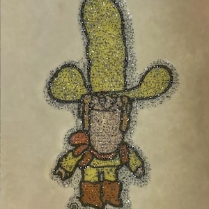 May include: A yellow glitter cowboy character with a big hat and boots. The character is wearing a red bandana and a yellow shirt. The text "BIG YELLA" is printed below the character.