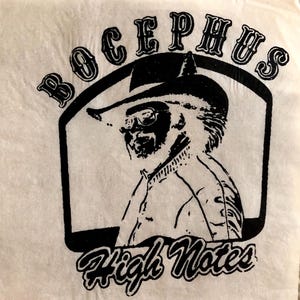 May include: A black and white graphic print featuring a side profile of a person wearing a cowboy hat and sunglasses. The text "BOCEPHUS" is arched above the figure, and the text "High Notes" is written in a cursive font below the image.