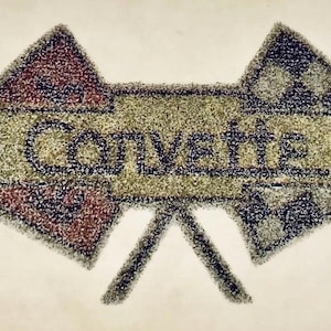 May include: A tufted rug featuring the Corvette logo with a central horizontal bar displaying the text Corvette in dark blue. The design includes two crossed flags, one with a red section and one with a black and white checkered pattern.
