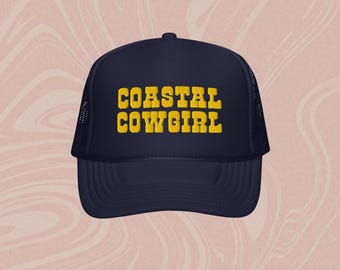 May include: A navy blue trucker hat with a yellow embroidered design that says "COASTAL COWGIRL".