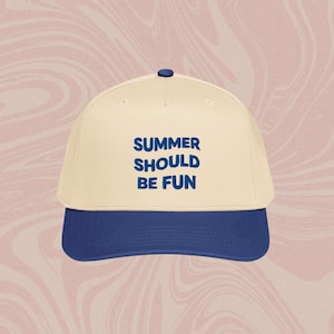May include: A baseball cap with a cream-coloured crown and a navy blue brim. The text "SUMMER SHOULD BE FUN" is printed in navy blue on the front of the cap. The cap has a navy blue button on top.