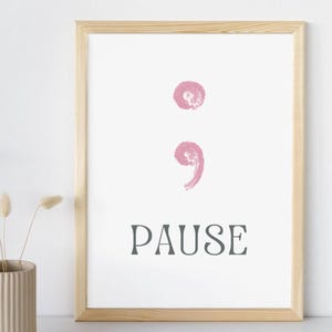 May include: A framed print with a pink semicolon symbol and the word "PAUSE" in black text.