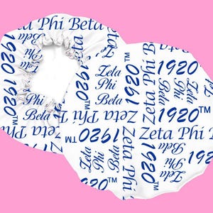 Puede incluir: Un gorro de ducha de satén blanco con texto azul que dice "Zeta Phi Beta 1920" repetido en todo el diseño.