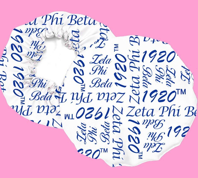 May include: A white satin hair bonnet featuring a repeating blue print of the text Zeta Phi Beta and the year 1920 with a trademark symbol. The bonnet has a gathered elastic edge designed to secure the fabric in a circular shape.