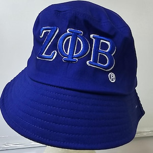 May include: A blue bucket hat with a white embroidered logo that says "ZΦB" with a registered trademark symbol.