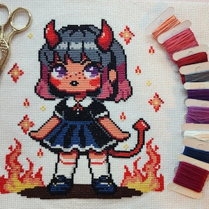 May include: Cross-stitch pattern of a cartoon girl with red horns and a blue dress, standing in front of orange flames. The girl has purple hair and blue eyes.