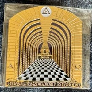 Puede incluir: Placa de metal de color dorado con un símbolo masónico y el texto "Royal & Select Master". La placa presenta un diseño de un pasillo con arcos y un suelo de ajedrez.