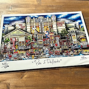 May include: A colorful illustration of a cityscape with buildings and street scenes. The illustration is titled "Pubs of DaHawks" and is numbered 217/250.