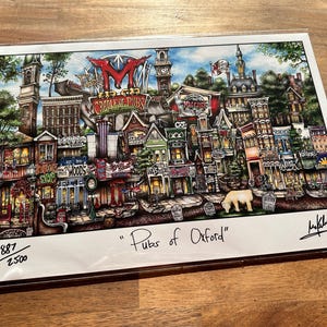 May include: A colorful illustration of a city street scene with buildings and shops. The illustration is titled "Pubs of Oxford" and is signed by the artist. The image is numbered 887/2500.