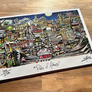 May include: A colorful illustration of a city street scene with buildings, shops, and signs. The image is titled "Pubs of Athens" and is numbered 344/2500.