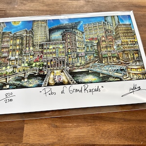 May include: A colorful print of a city at night, featuring buildings, bridges, and a river. The artwork is titled "Pubs of Grand Rapids" and includes a signature and edition number.