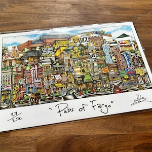 May include: A colorful print titled "Pubs of Fargo" featuring a detailed illustration of a city street with various businesses and neon signs. The artwork includes the text "Fargo" and is signed by the artist.